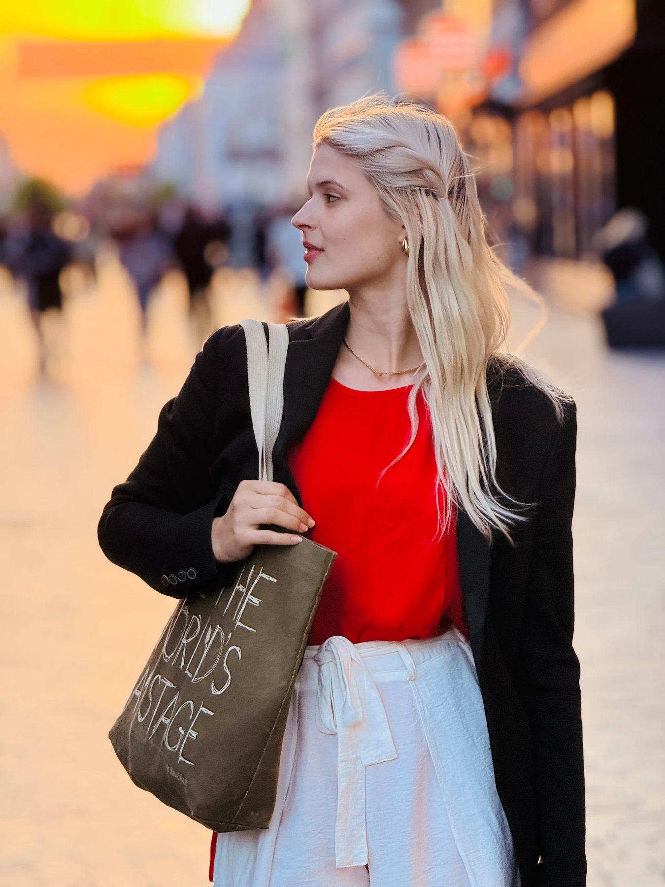 Street portrait of a woman in a red top, with warm sunset light and a softly blurred background.